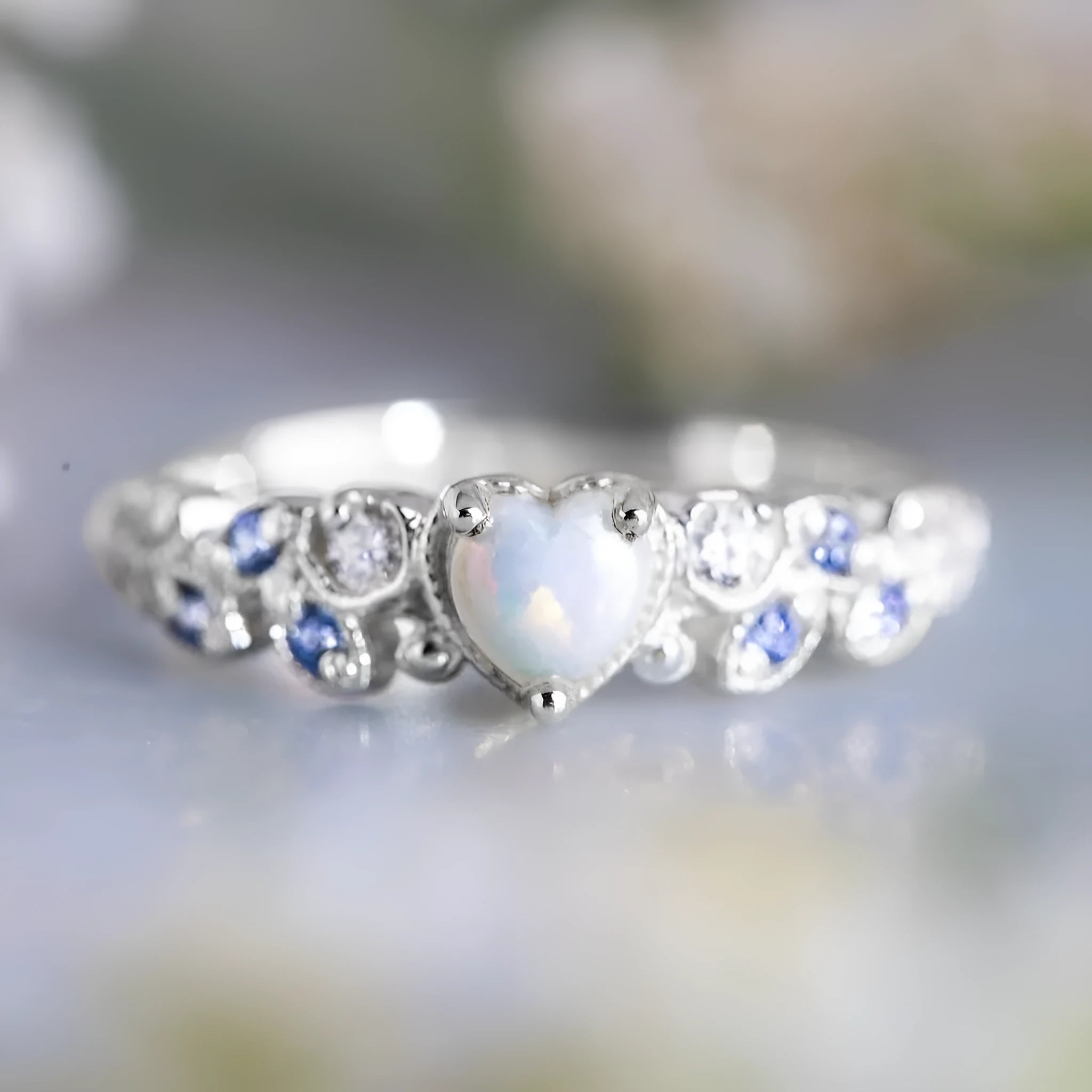 Close-up of a white alloy women's ring with a heart shape and flower opal ocean pattern detail.