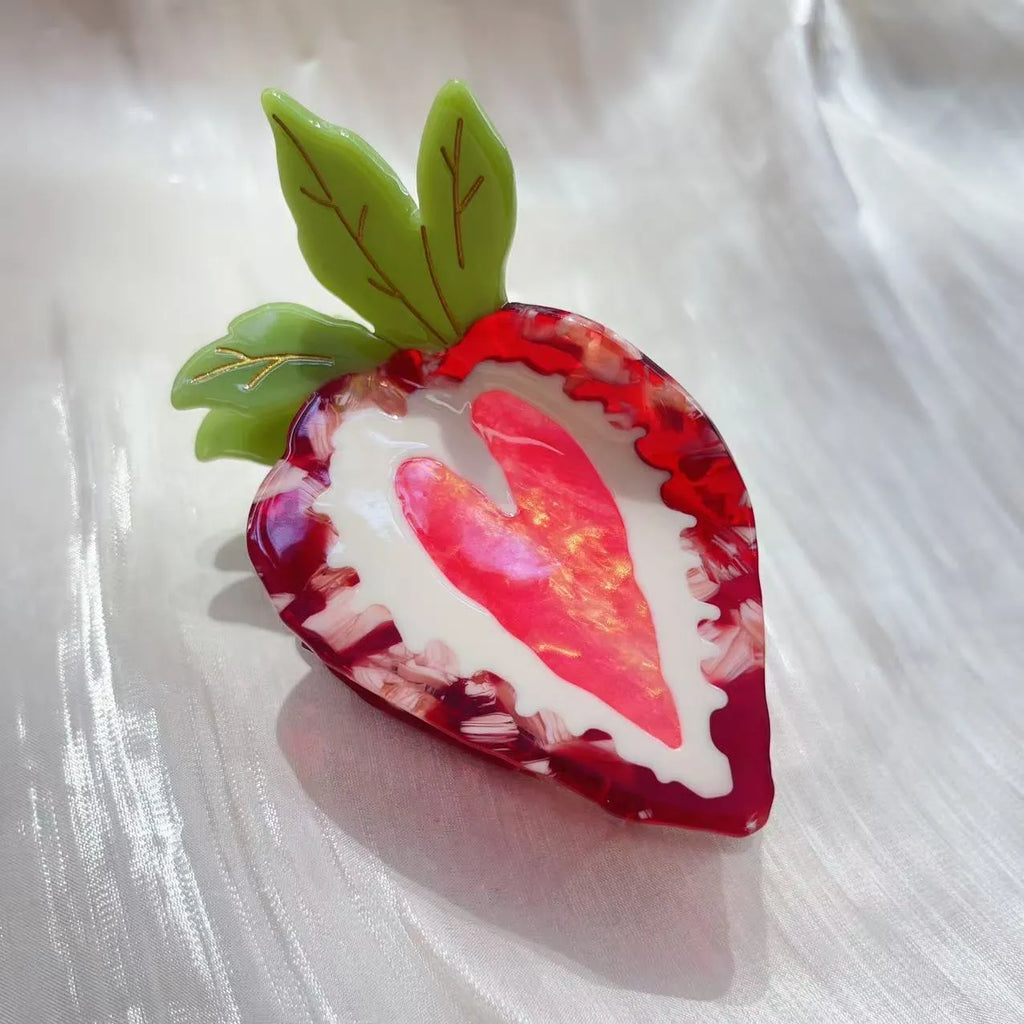 Handmade red strawberry hairpin with green leaves and a pink bow tie on a hair model.