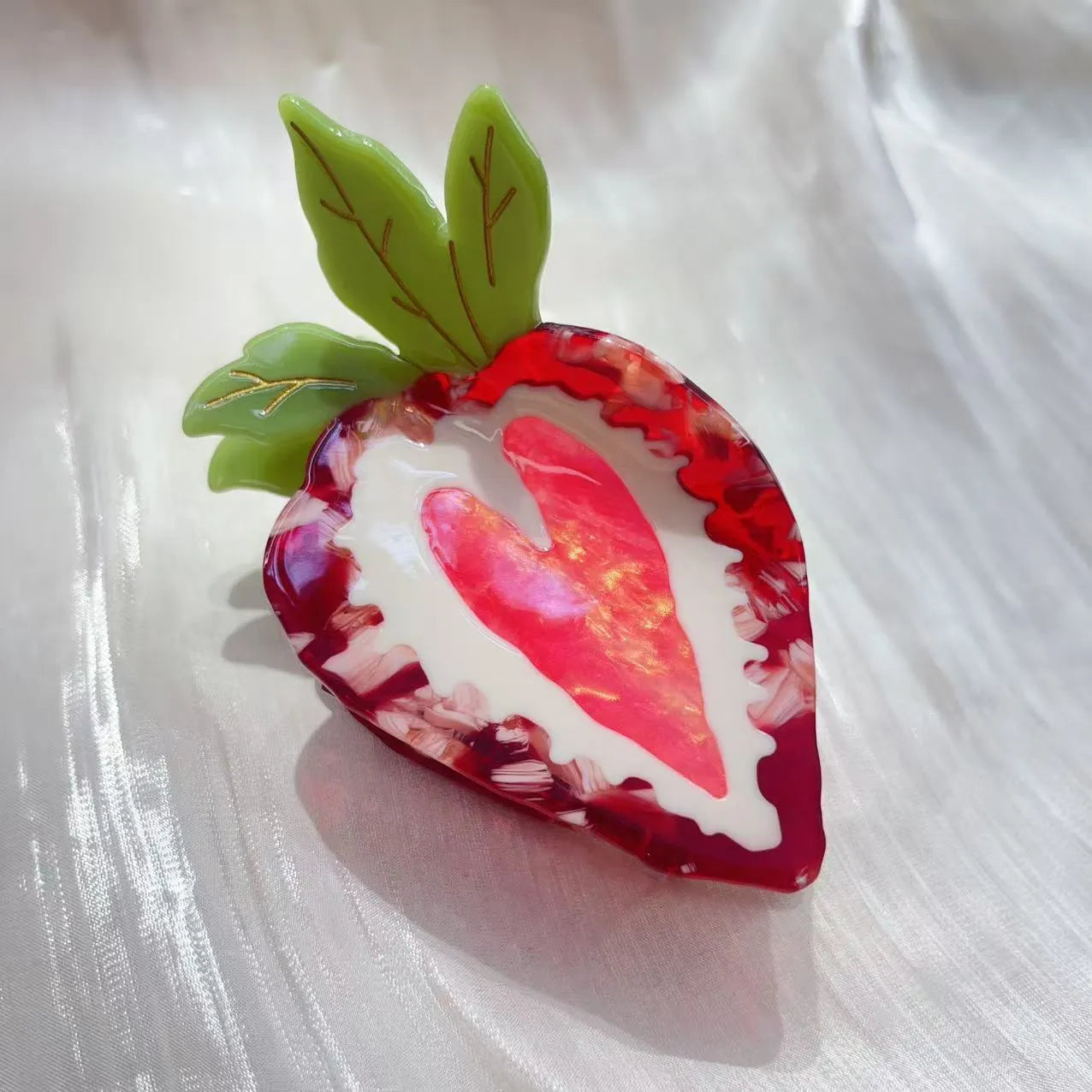 Handmade red strawberry hairpin with green leaves and a pink bow tie on a hair model.