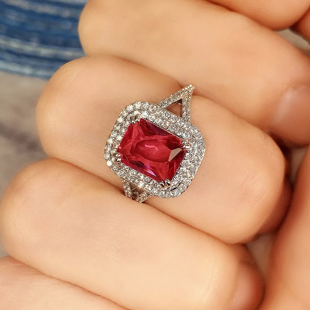 Red square rhinestone set in a copper women's ring on a grey background.