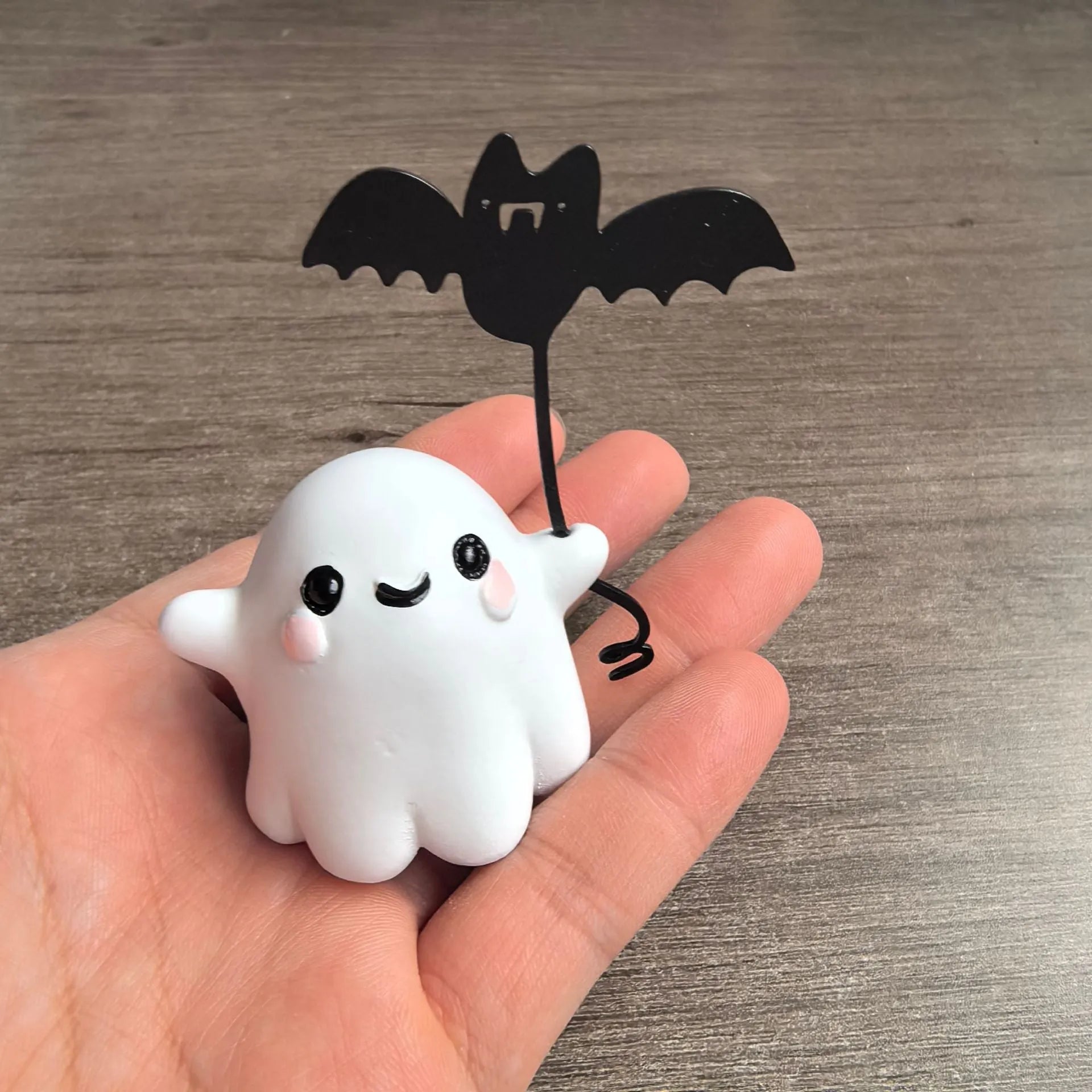 Small resin statue of a ghost walking a dog, holding a bat, for Halloween decoration.