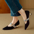 Black women's stiletto high heel shoes with buckle fastening and pointed toe on a solid background.