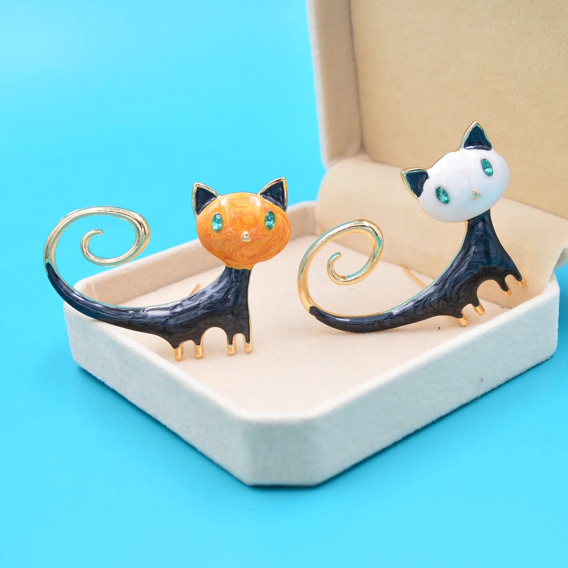 Close-up of a white alloy brooch shaped like a cat with an orange painted tail.