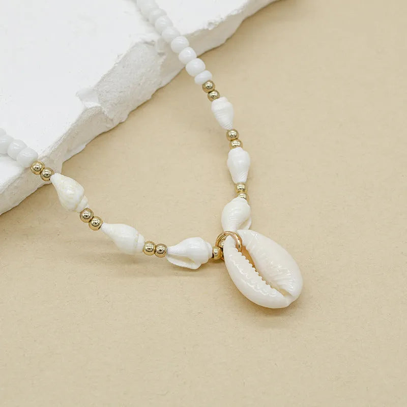 White conch shell pendant necklace with a cold wind pattern design on a silver-toned chain.