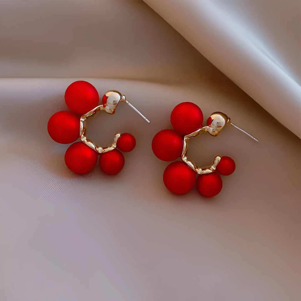 A pair of silver-tone alloy drop earrings with a red bell charm, shown against a plain background.
