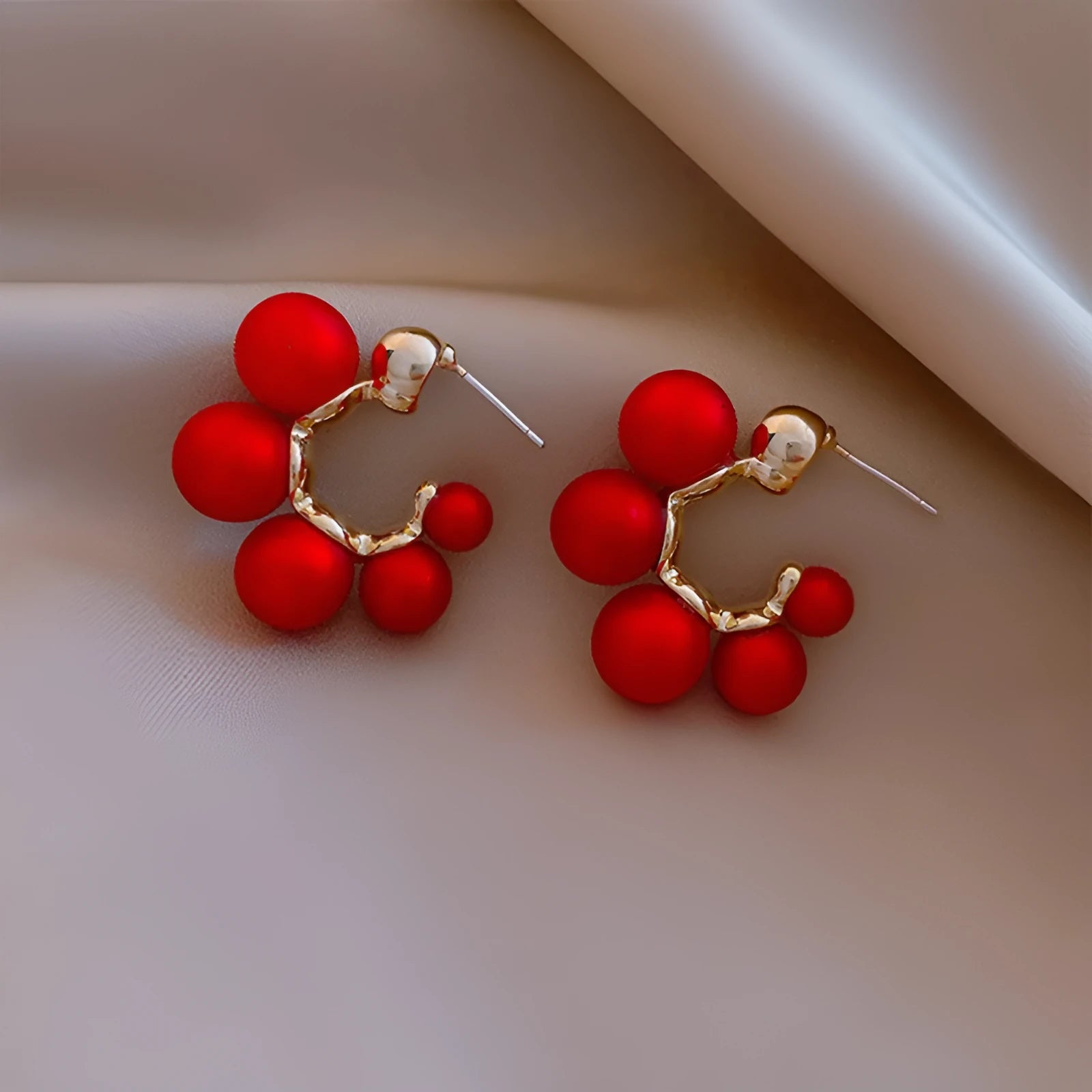 A pair of silver-tone alloy drop earrings with a red bell charm, shown against a plain background.