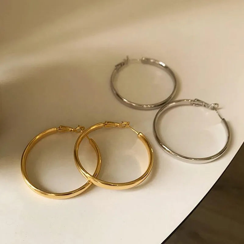A pair of large gold-coloured metal circle hoop earrings on a white background