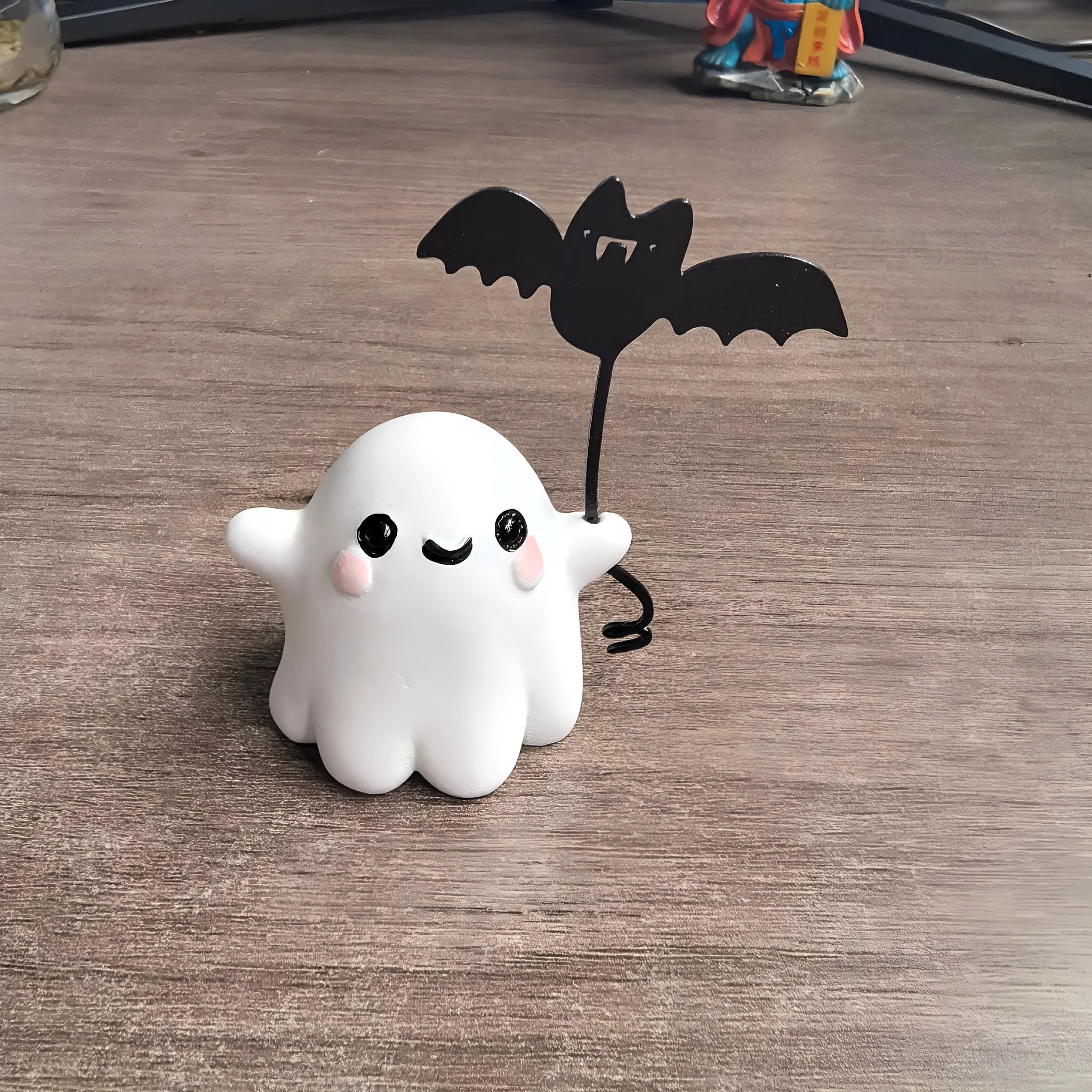 Small resin statue of a ghost walking a dog, holding a bat, for Halloween decoration.