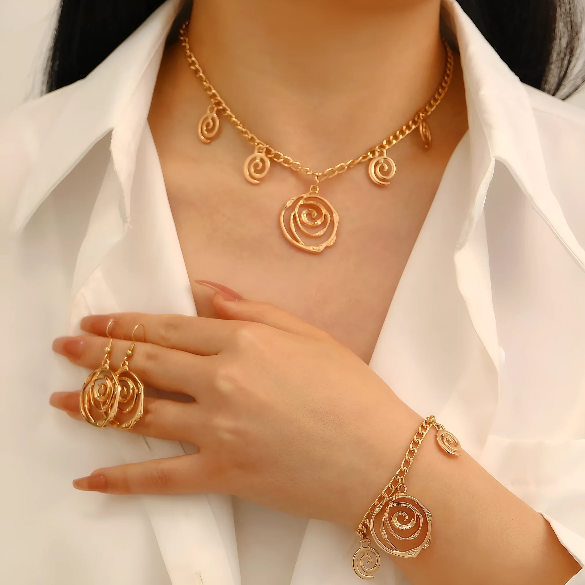 Gold tone donut spiral necklace, bracelet, and earrings set on a white background.