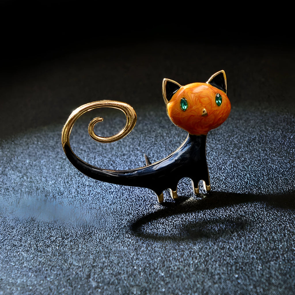 Close-up of a white alloy brooch shaped like a cat with an orange painted tail.