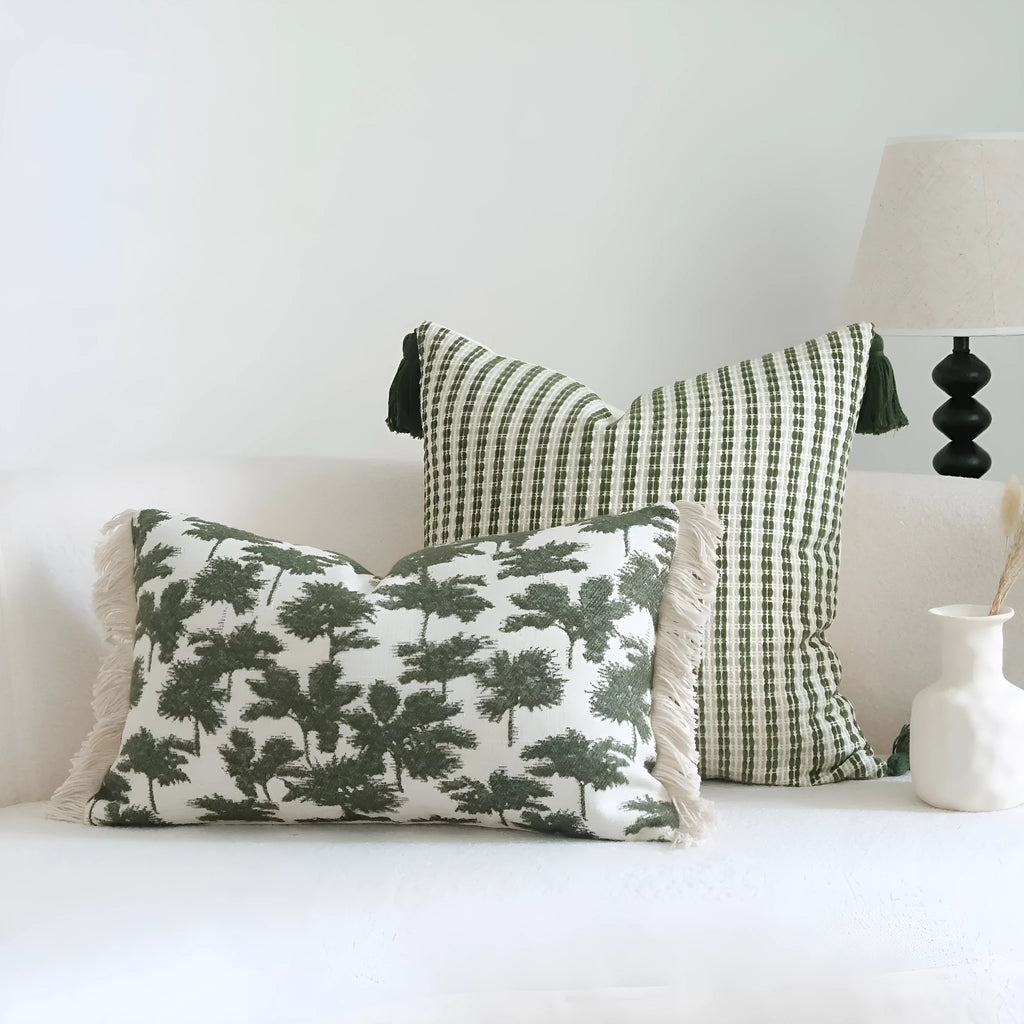 Green cotton linen hotel sample pillow with tassel design and silk floss filling on bed.