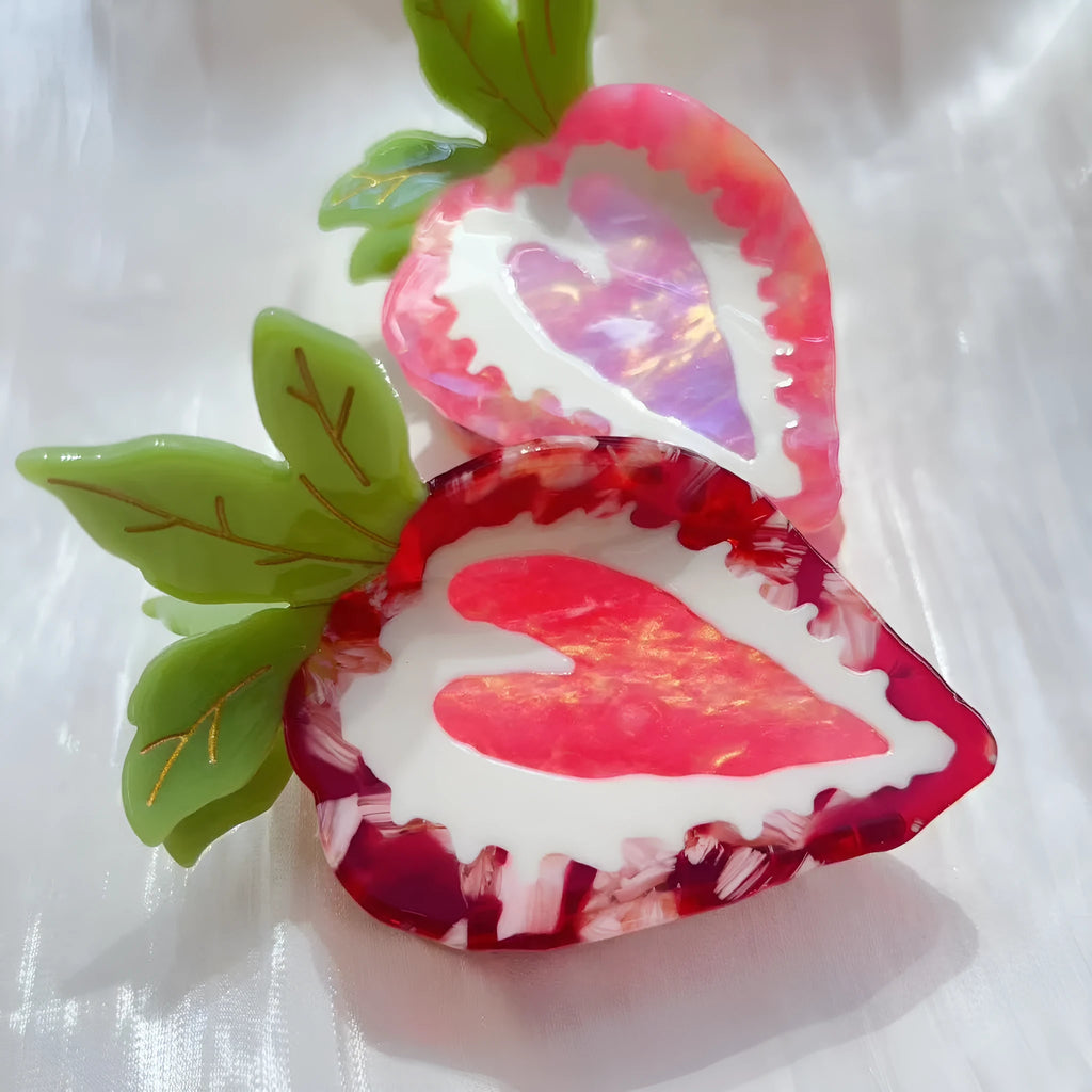 Handmade red strawberry hairpin with green leaves and a pink bow tie on a hair model.
