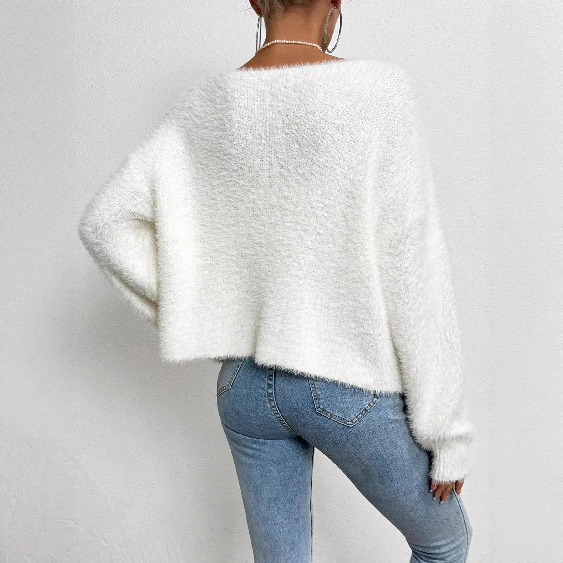 White women's V-neck cardigan sweater with bead knit texture on a hanger.