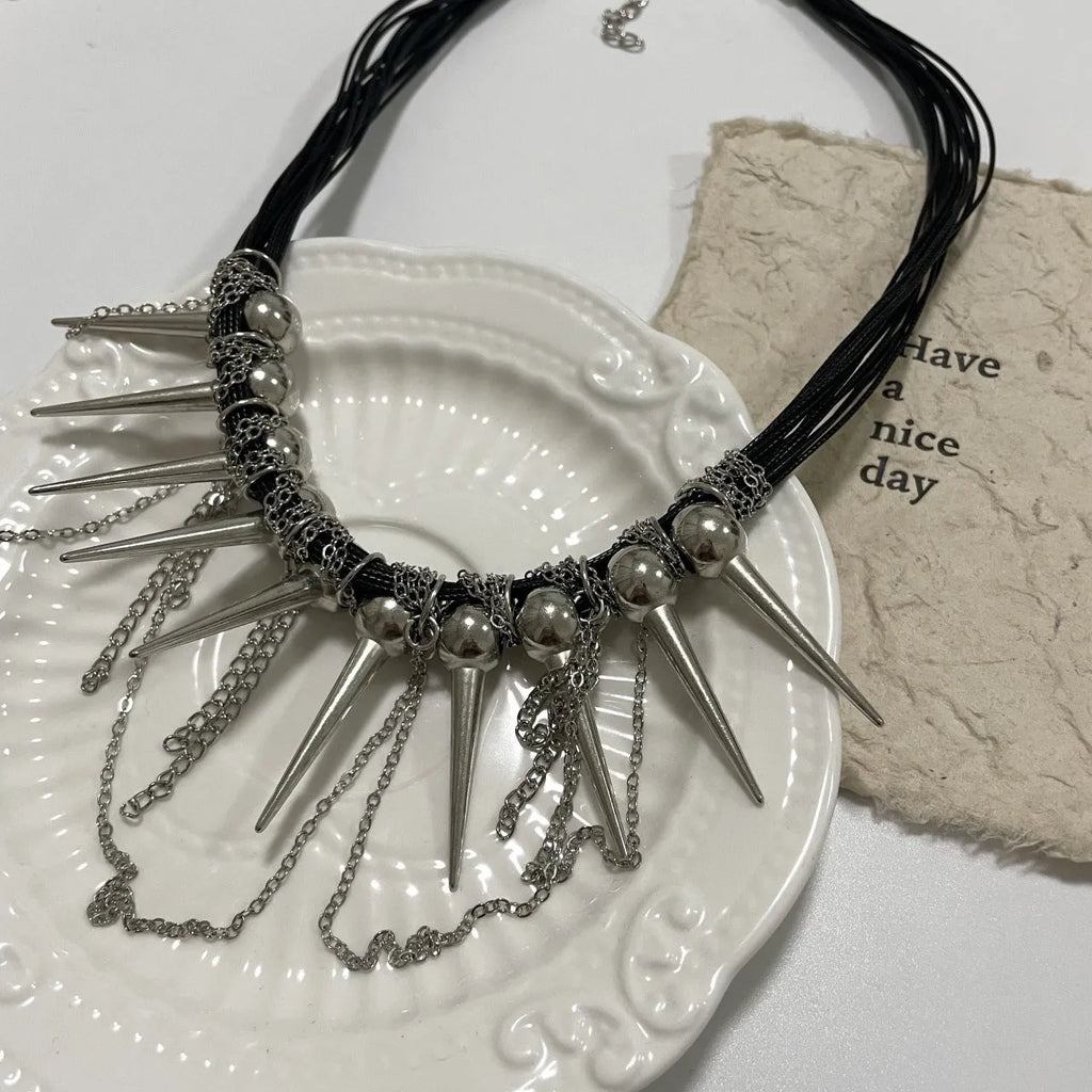 Leather necklace with electroplated rivets, round beads, and a tassel in a winding casual design