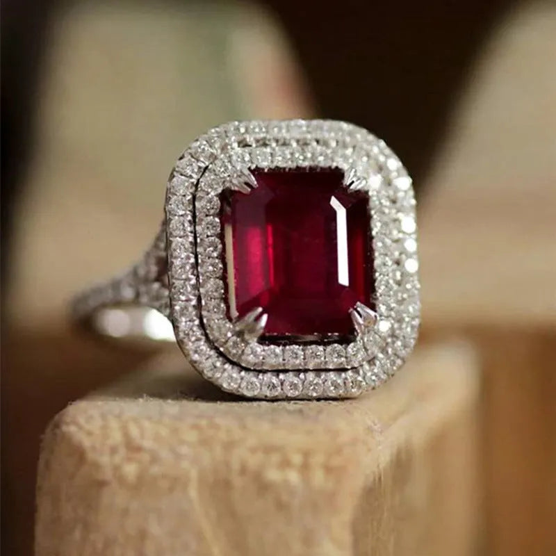Red square rhinestone set in a copper women's ring on a grey background.