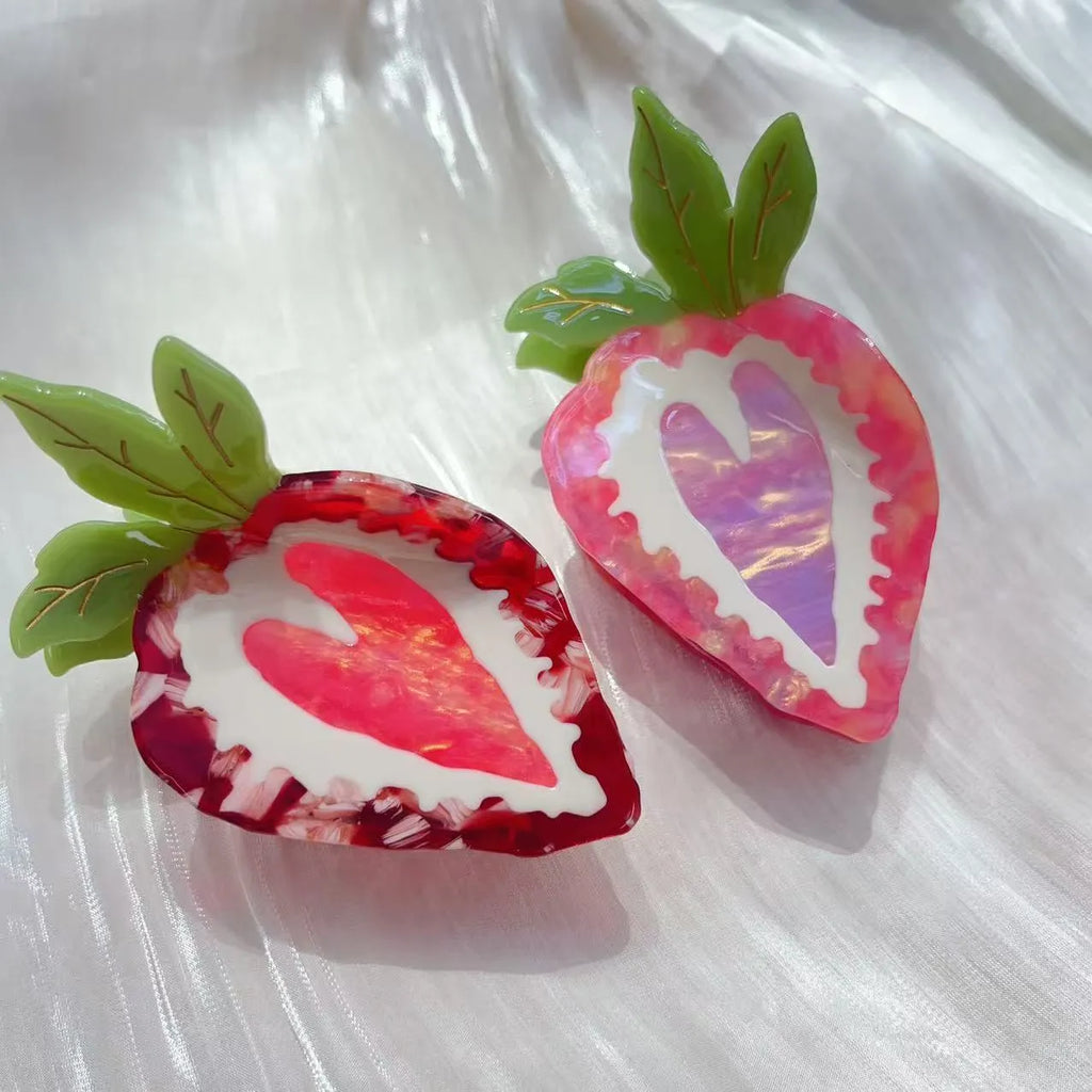 Handmade red strawberry hairpin with green leaves and a pink bow tie on a hair model.