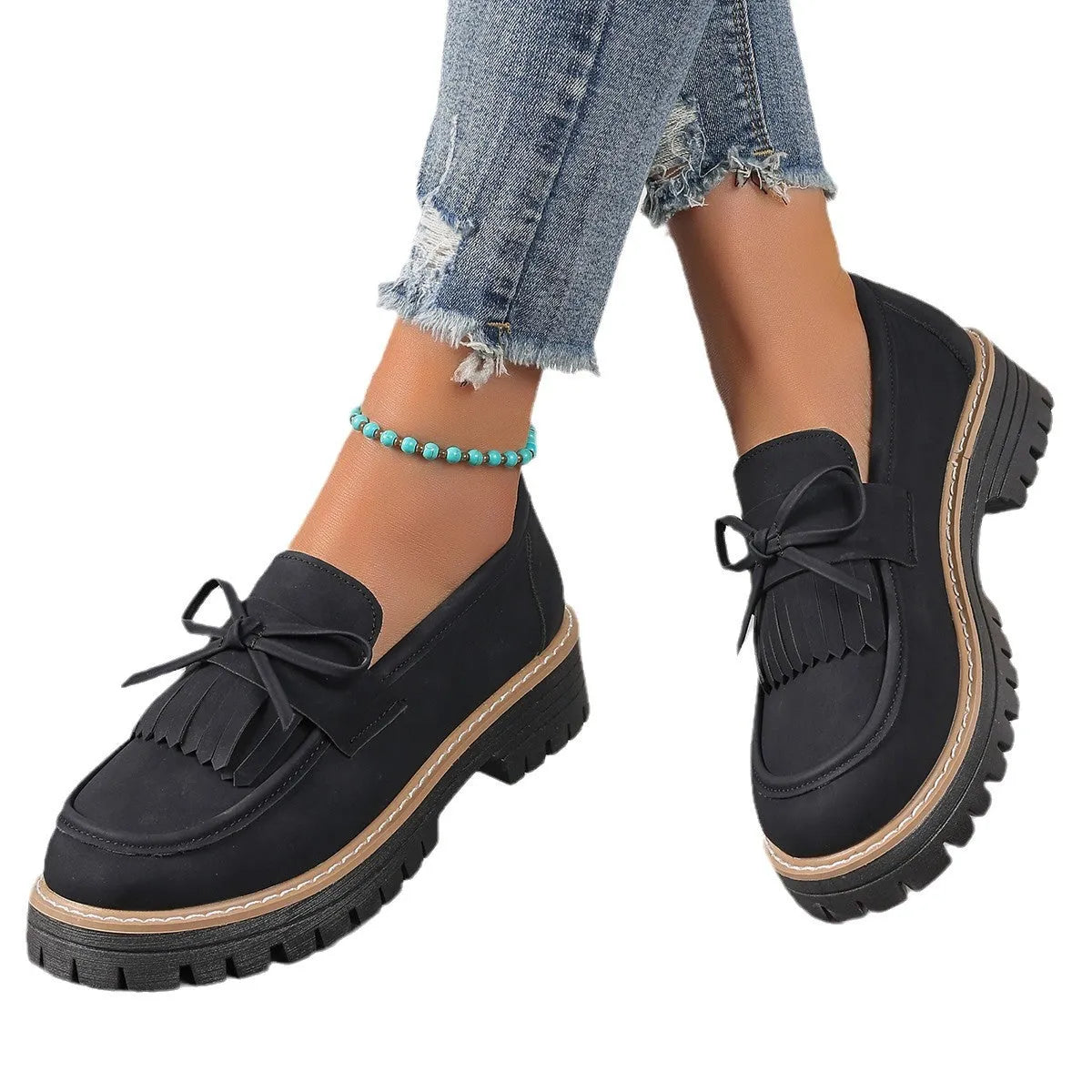 Black and brown women's tassel loafers with a chunky heel and bowknot detail on a rubber sole.
