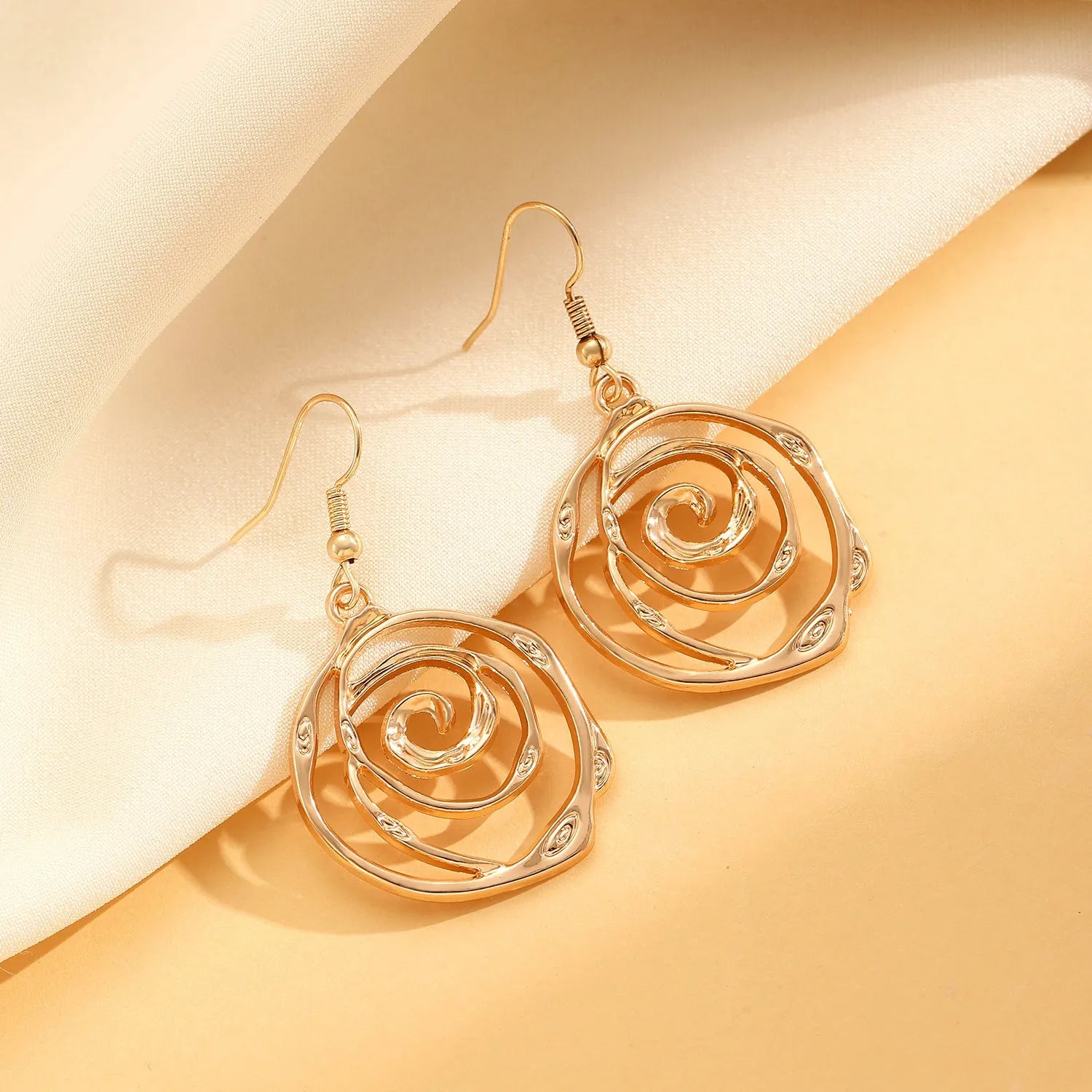 Gold tone donut spiral necklace, bracelet, and earrings set on a white background.