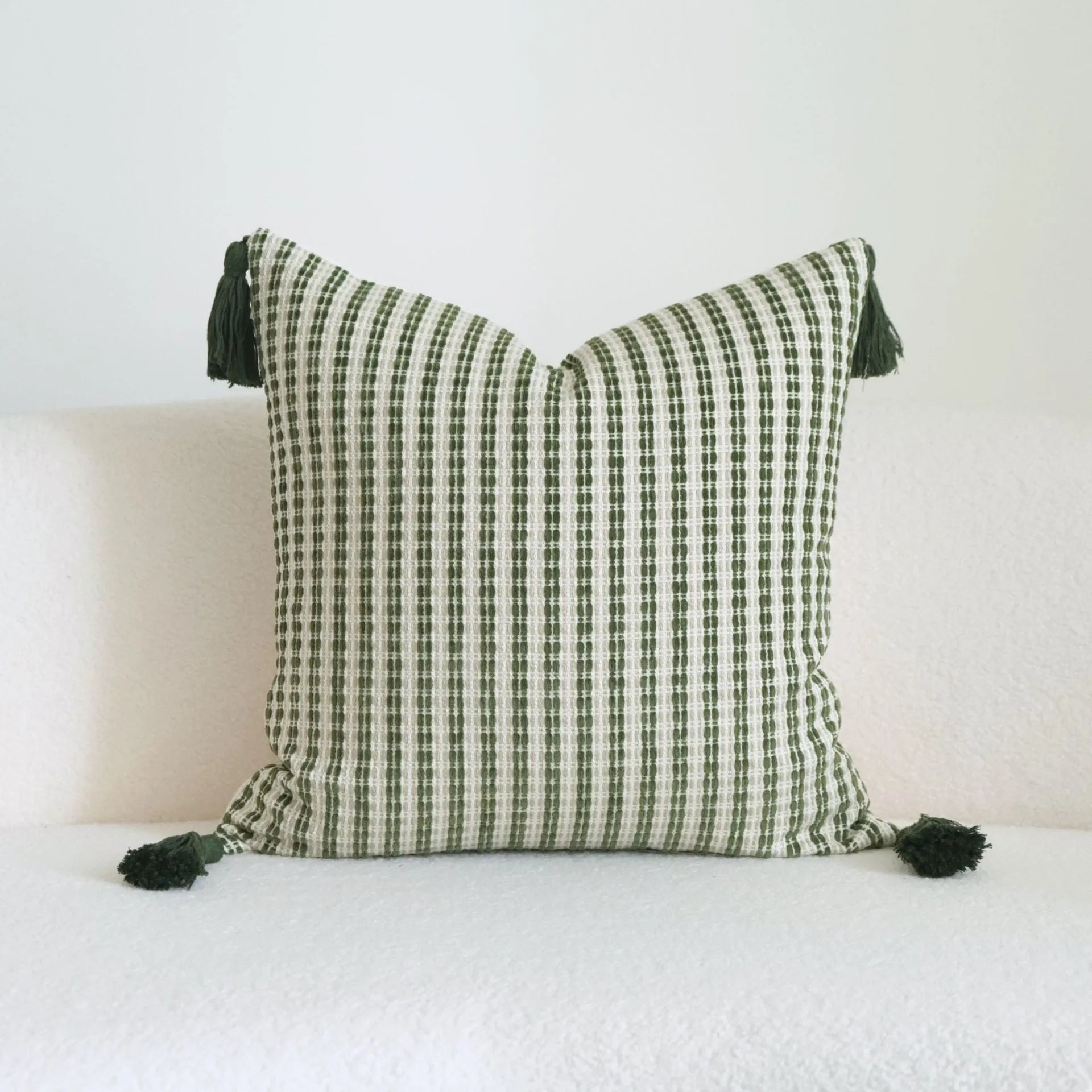 Green cotton linen hotel sample pillow with tassel design and silk floss filling on bed.