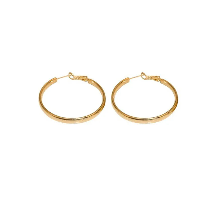 A pair of large gold-coloured metal circle hoop earrings on a white background