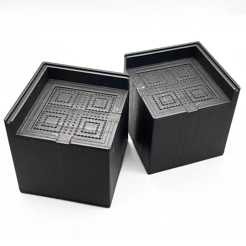 Four black thickened plastic bed foot mats arranged together for furniture height increase and floor protection