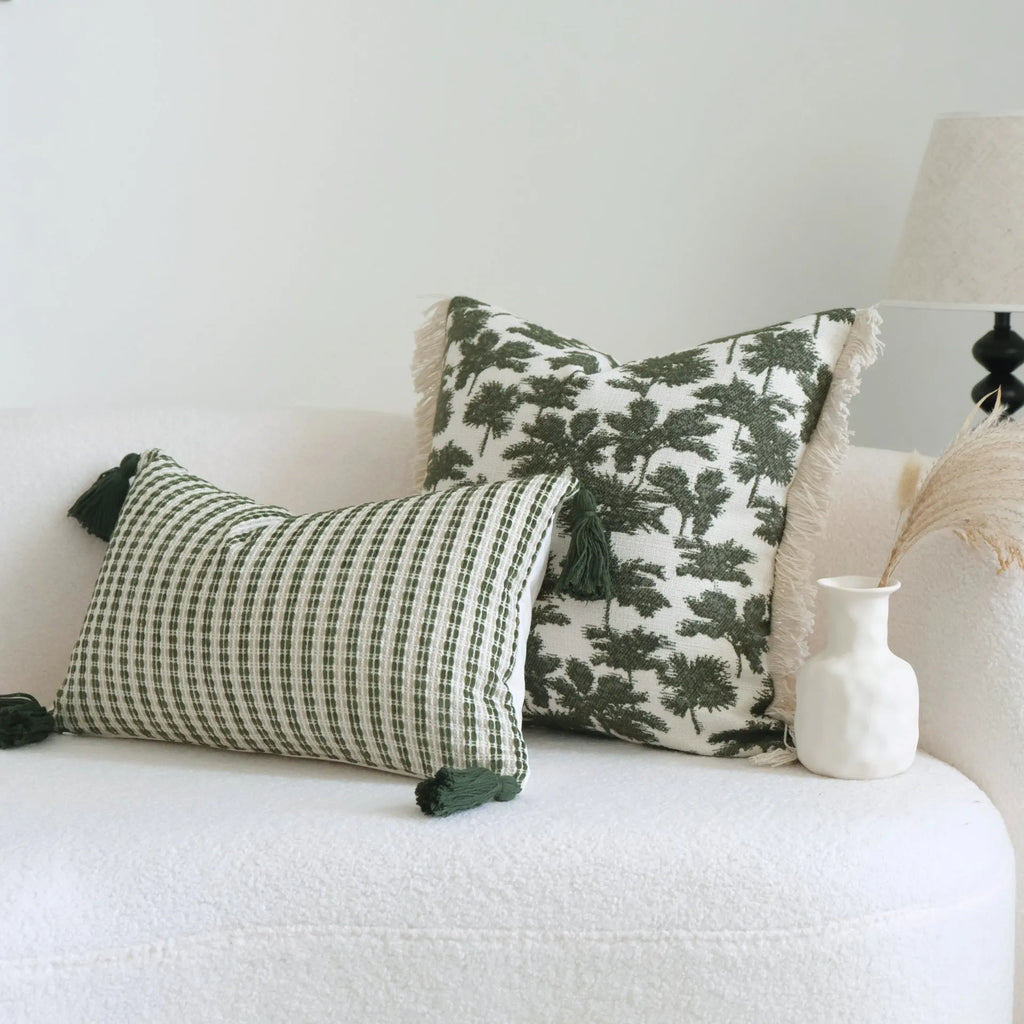 Green cotton linen hotel sample pillow with tassel design and silk floss filling on bed.