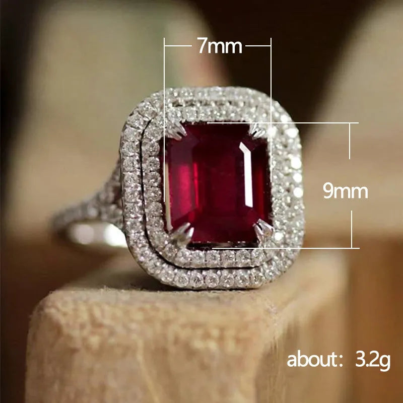 Red square rhinestone set in a copper women's ring on a grey background.