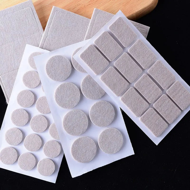 Assorted beige plastic furniture leg protectors in round and square shapes on hardwood floor