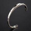 Open-ended stainless steel women's bracelet with inlaid zirconia stones in rose gold colour.