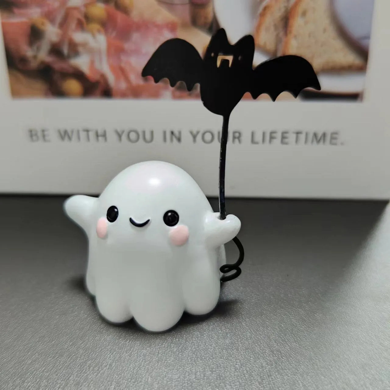 Small resin statue of a ghost walking a dog, holding a bat, for Halloween decoration.