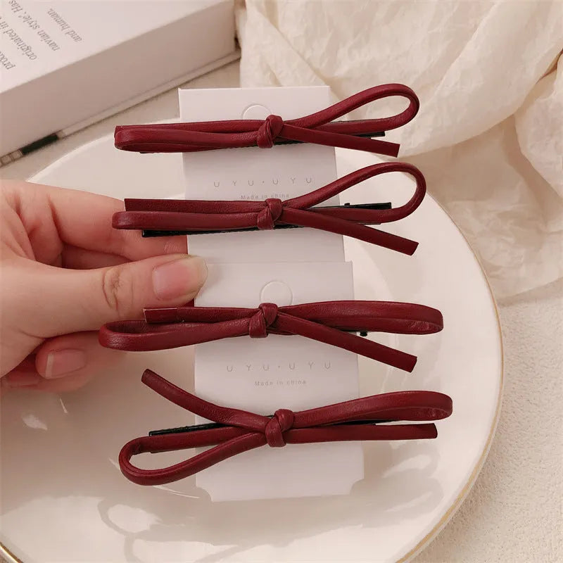 Wine red leather bow hair barrettes showing front and back views