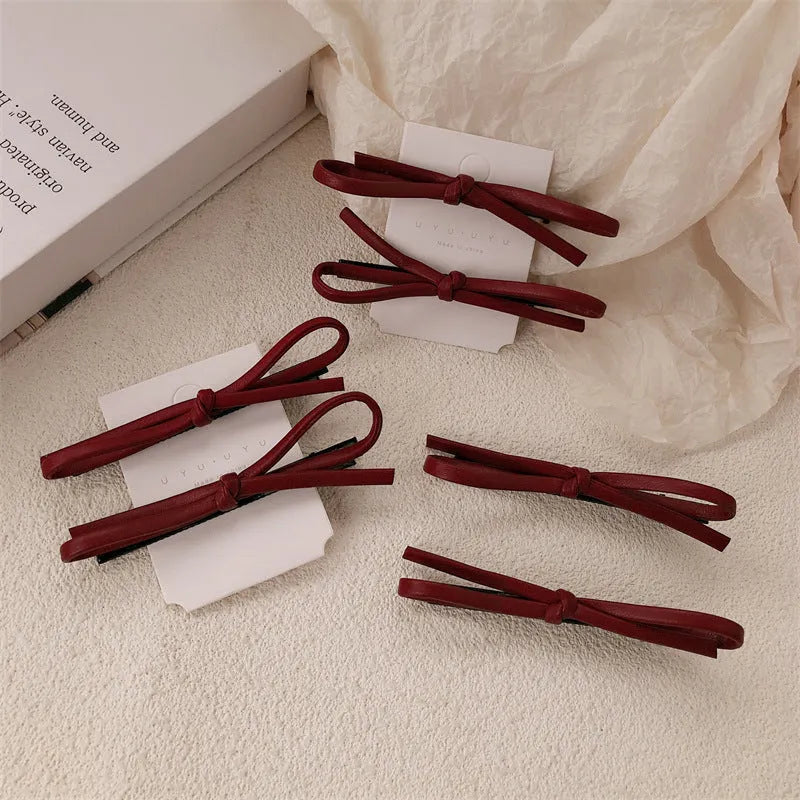 Wine red leather bow hair barrettes showing front and back views