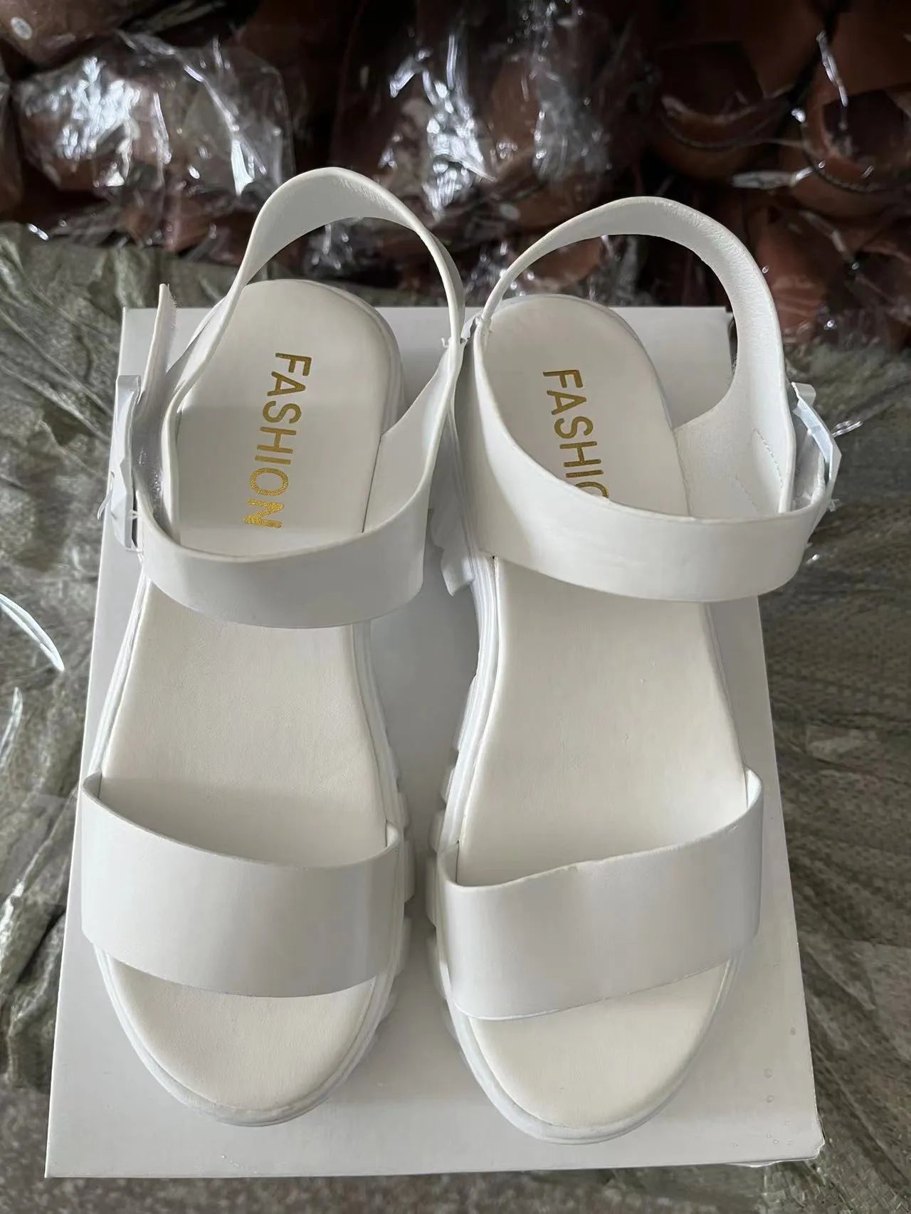 Women's beige peep toe ankle-strap buckle platform sandals with a fish mouth toe design on a wooden surface.