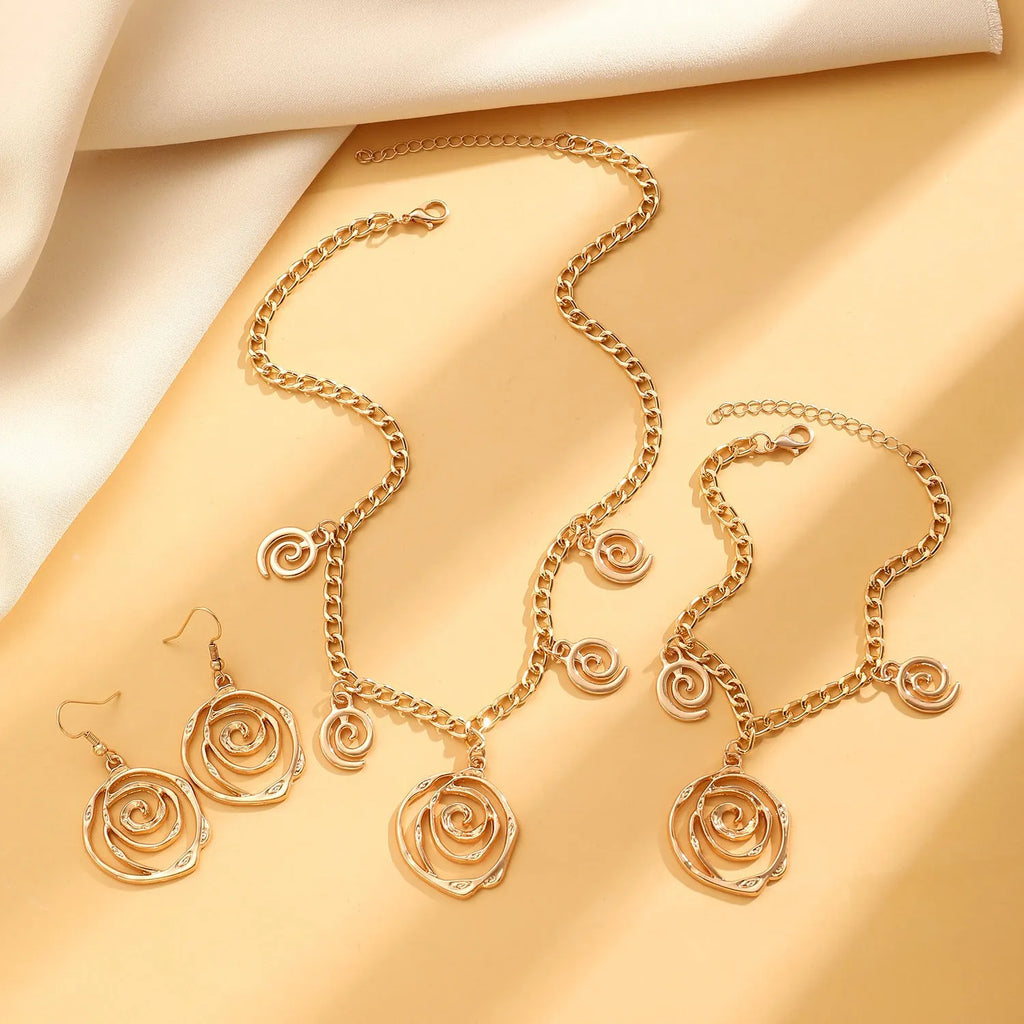 Gold tone donut spiral necklace, bracelet, and earrings set on a white background.