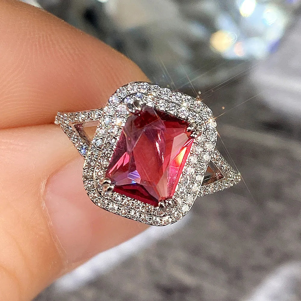 Red square rhinestone set in a copper women's ring on a grey background.