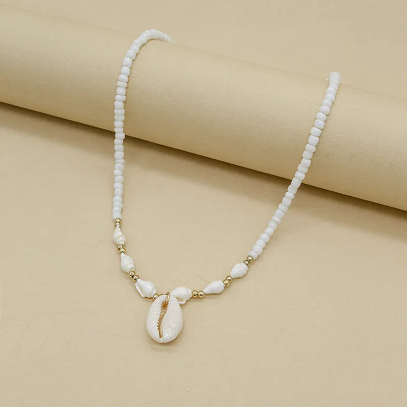 White conch shell pendant necklace with a cold wind pattern design on a silver-toned chain.