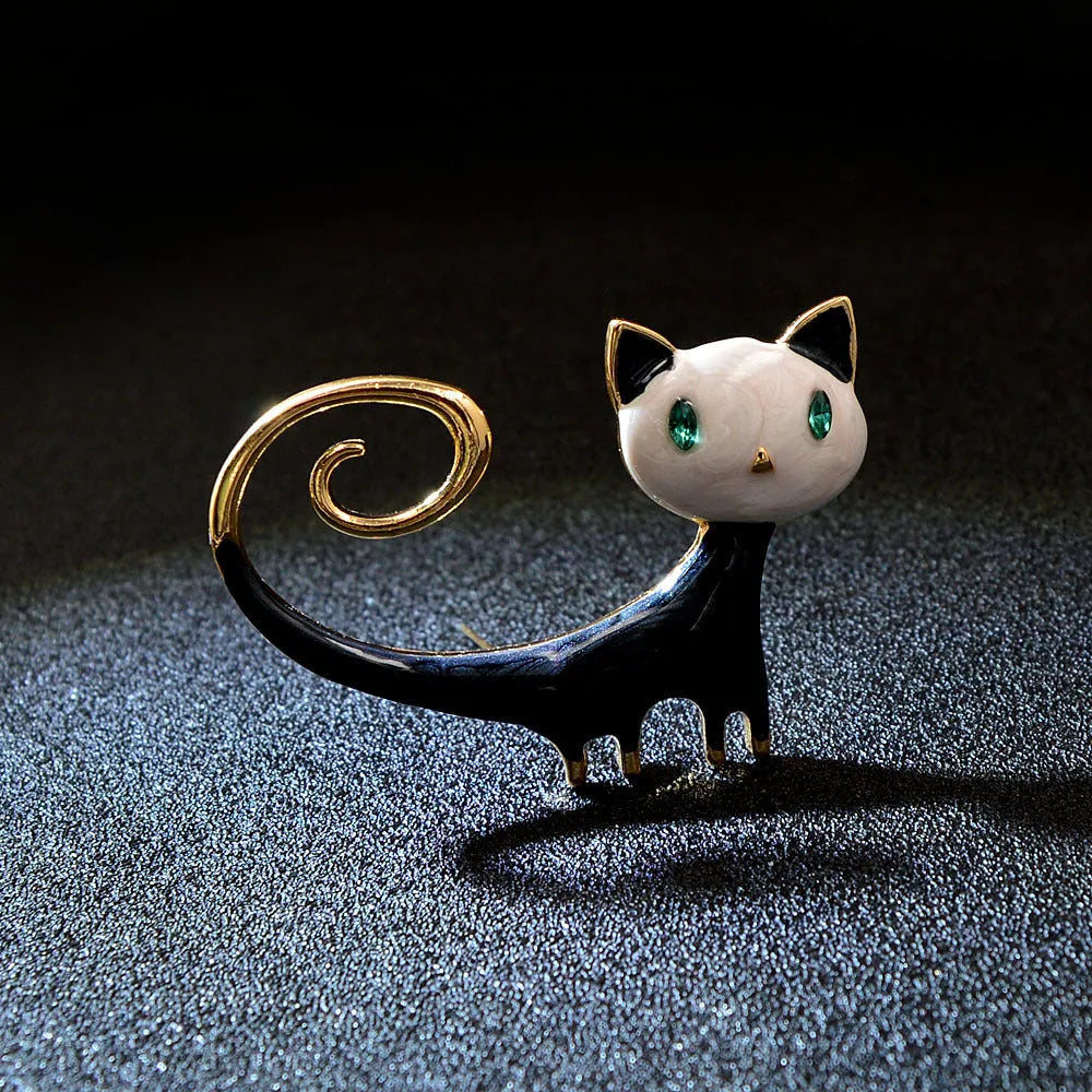 Close-up of a white alloy brooch shaped like a cat with an orange painted tail.