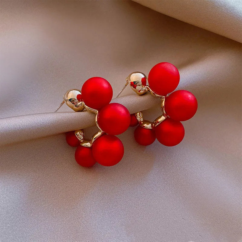 A pair of silver-tone alloy drop earrings with a red bell charm, shown against a plain background.