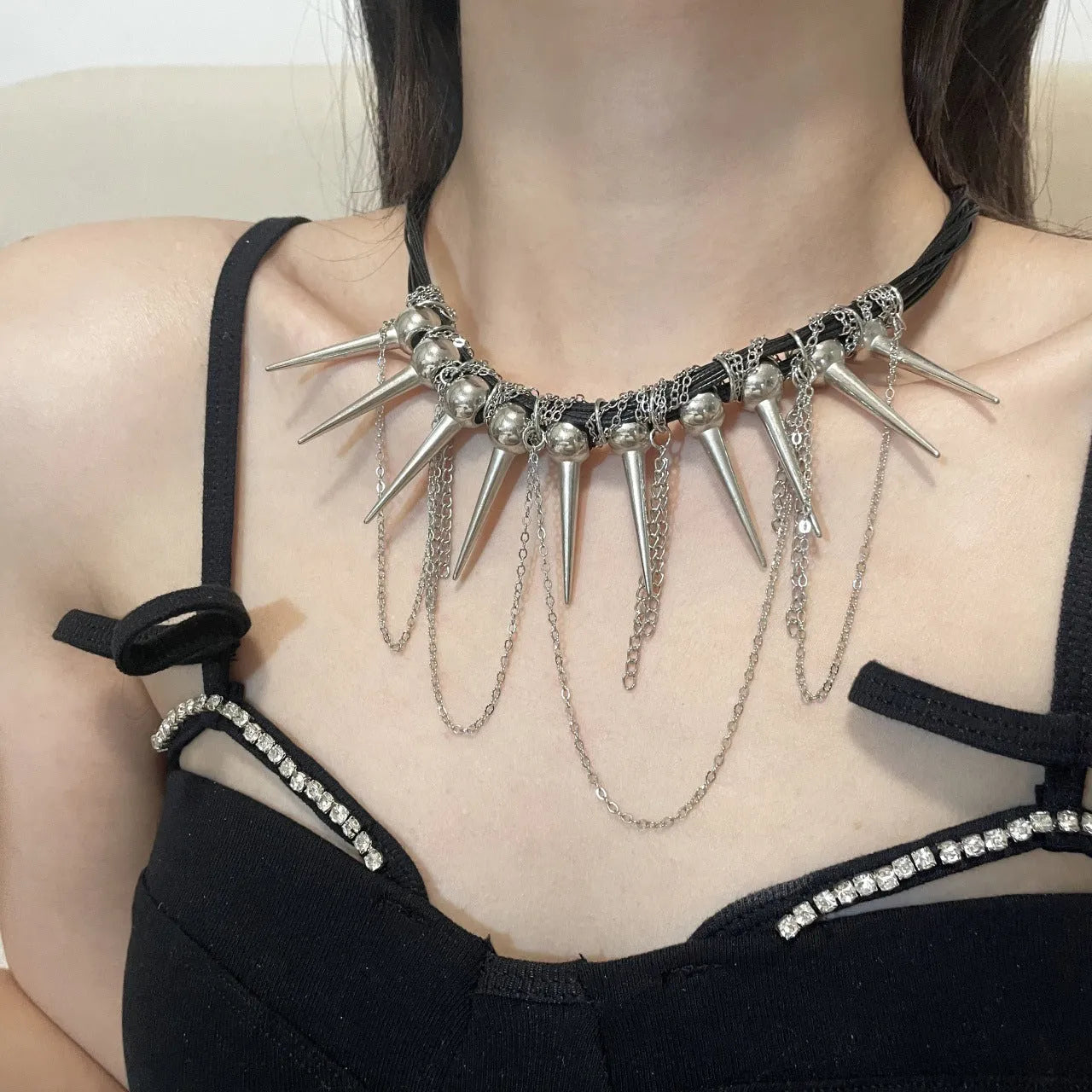 Leather necklace with electroplated rivets, round beads, and a tassel in a winding casual design