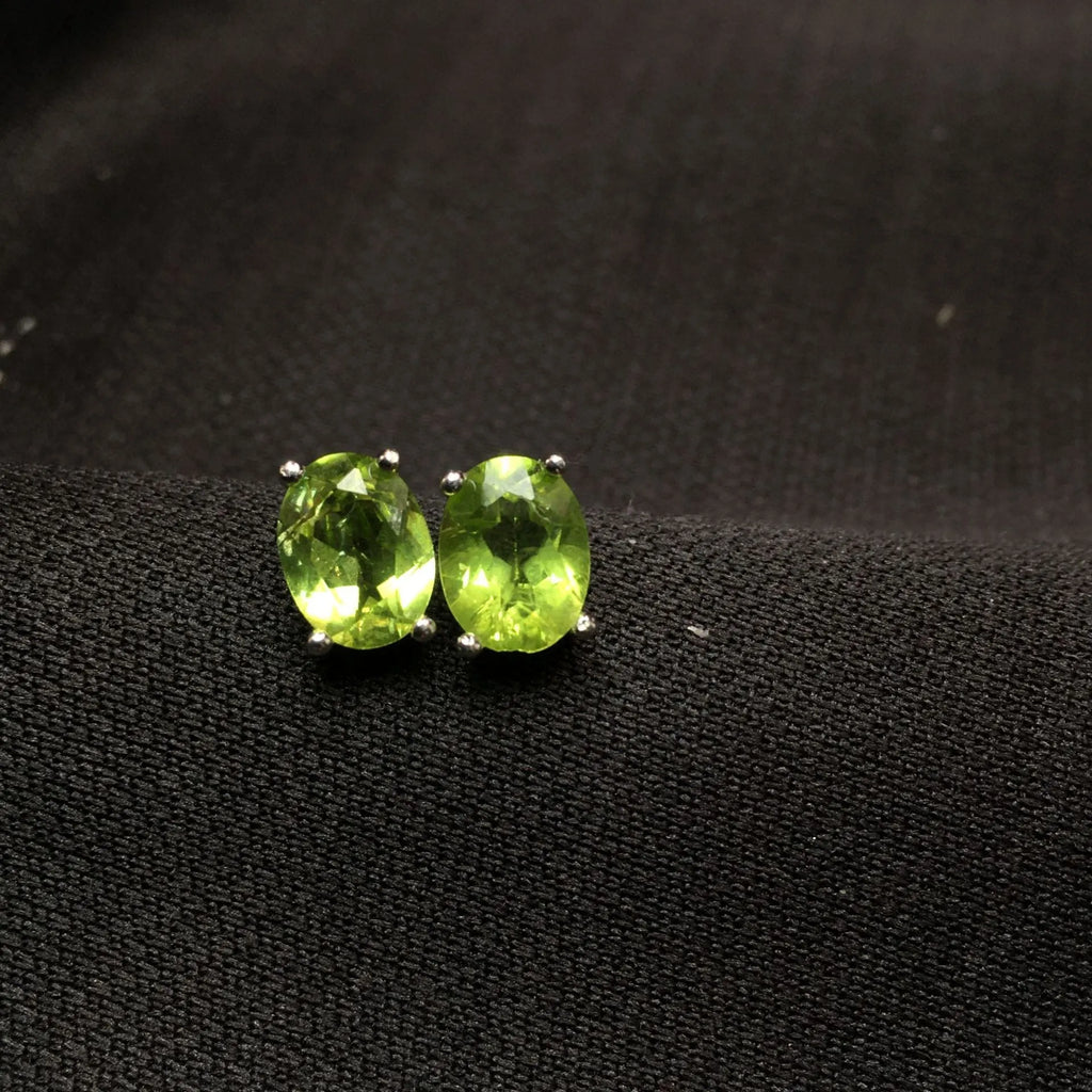 Natural grass green olivine faceted stud earrings set in S925 silver, showing oval stone shape.