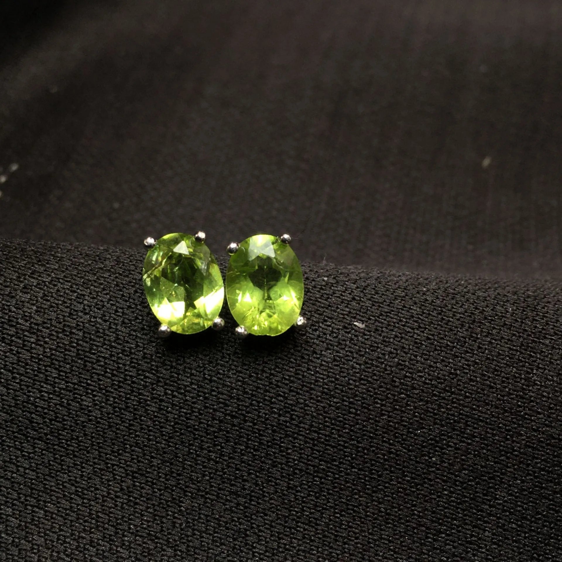 Natural grass green olivine faceted stud earrings set in S925 silver, showing oval stone shape.
