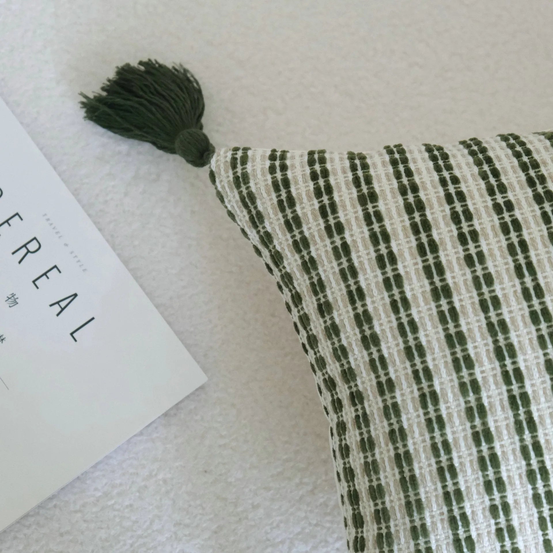 Green cotton linen hotel sample pillow with tassel design and silk floss filling on bed.