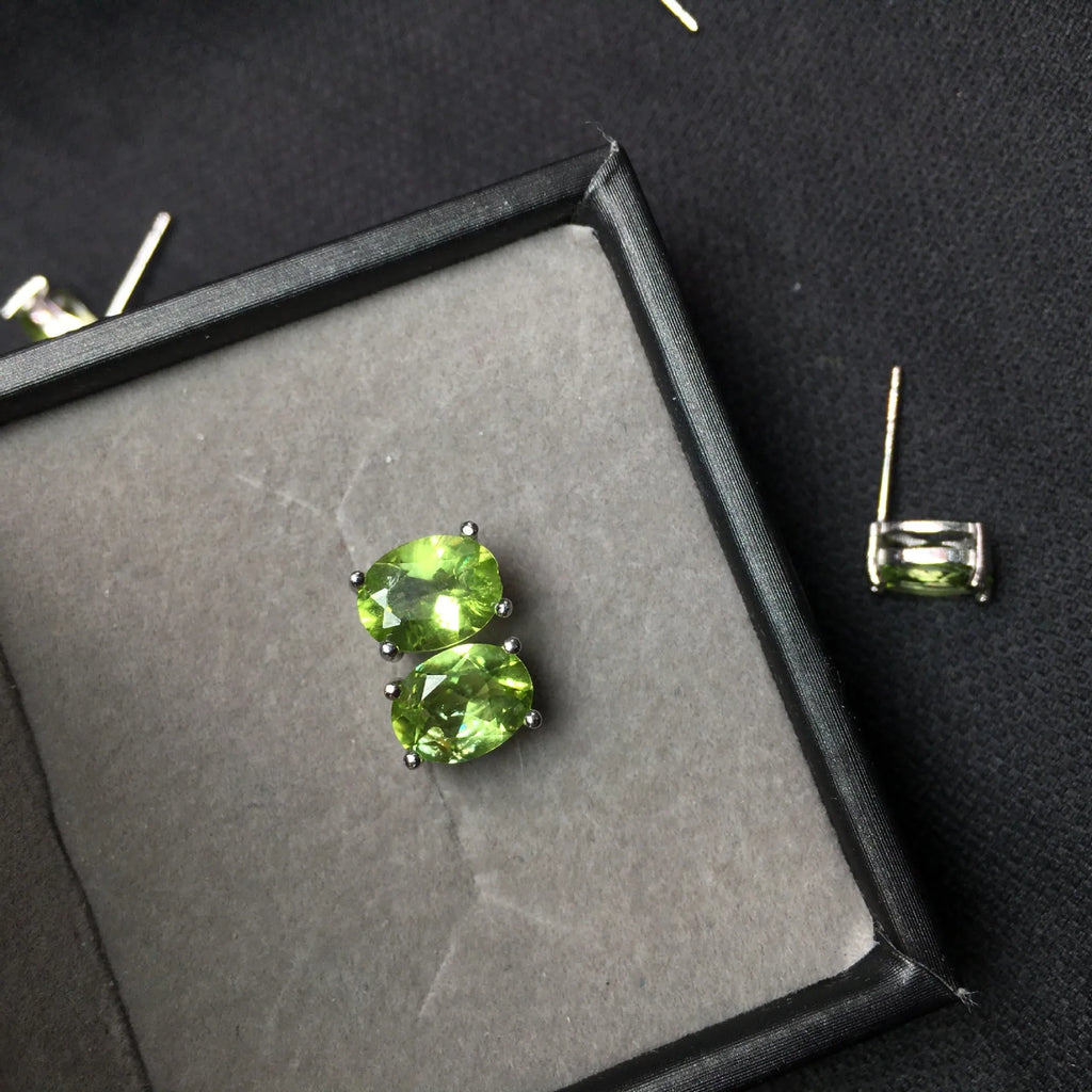 Natural grass green olivine faceted stud earrings set in S925 silver, showing oval stone shape.
