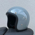 A cement grey retro-style half motorcycle helmet made from FRP glass fibre, shown on a white background.