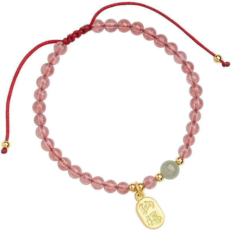 Hand-woven red rope bracelet with a strawberry quartz crystal charm on a wrist.
