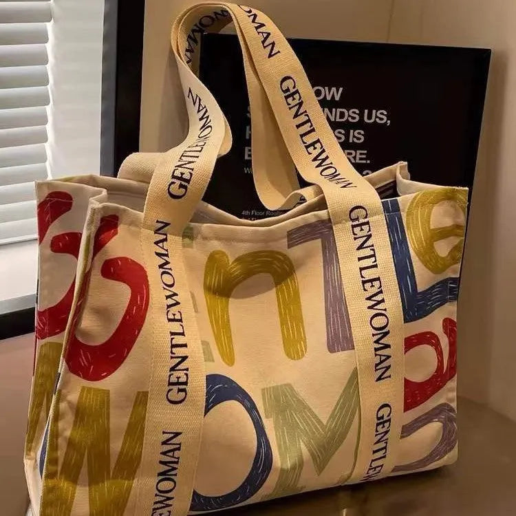 Large canvas tote bag with printed design showing black letters, available in multiple pattern options