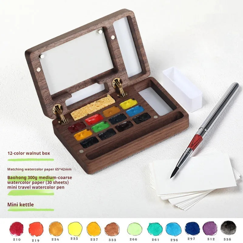 Small wooden watercolour paint box open to show artist pigment pans inside for portable painting.