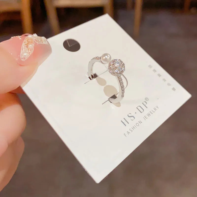 Open-end women's ring with round zircon stone on geometric band in gold or silver finish.