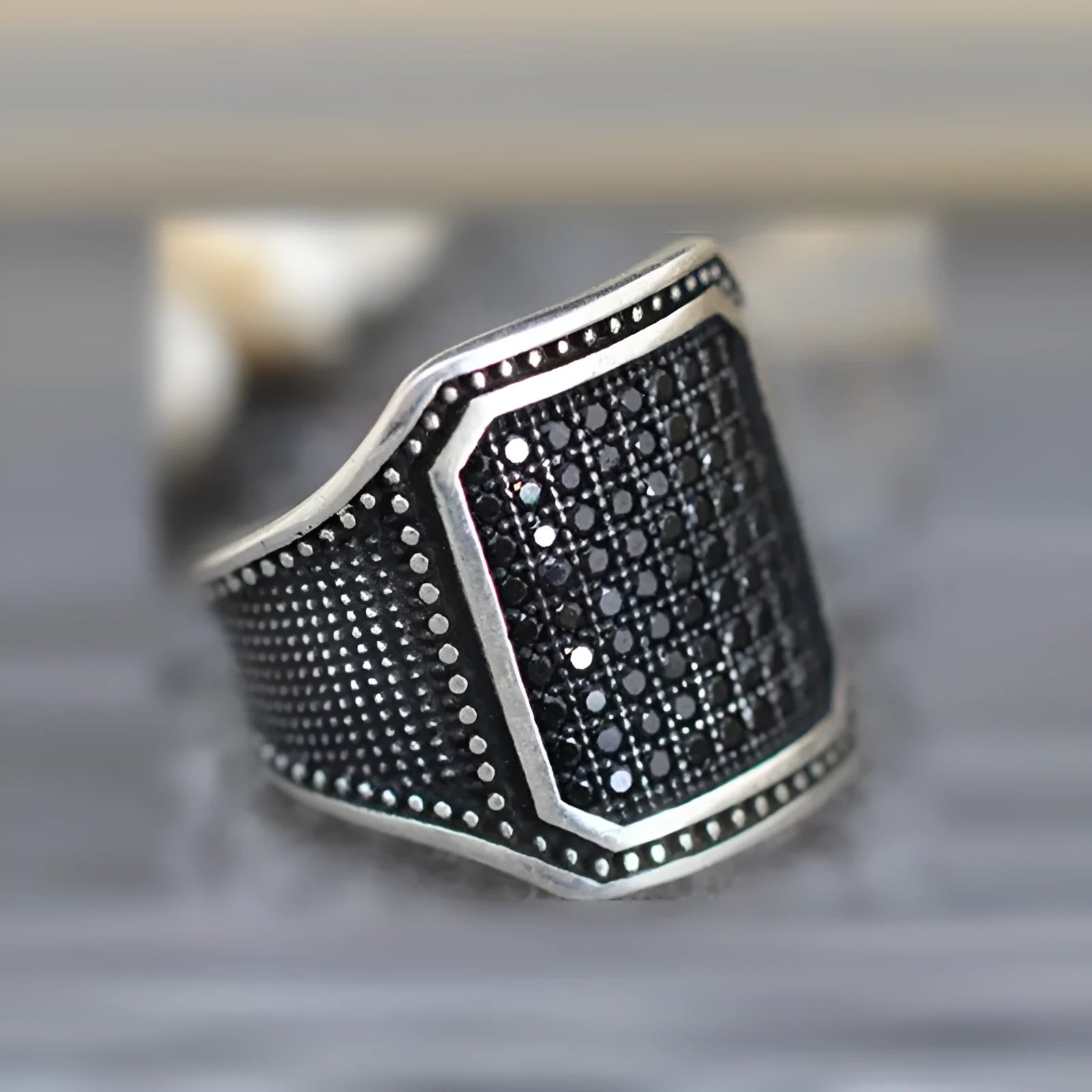 Black alloy ring with copper inlay and zircon stone detailing, shown on a finger.
