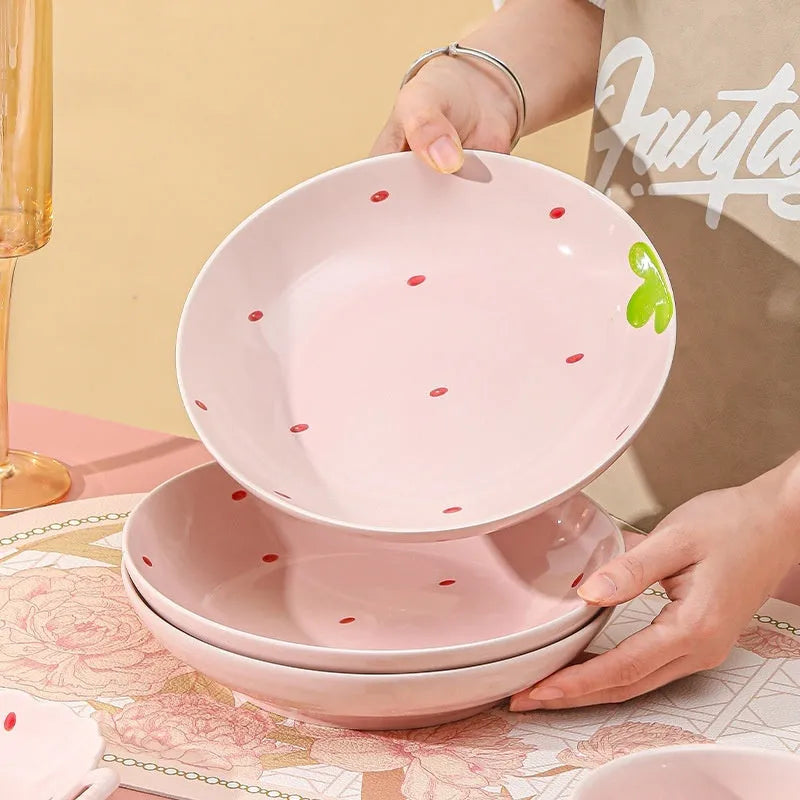 Porcelain dinnerware set with strawberry design: bowl, plate, and twist-handle spoon.